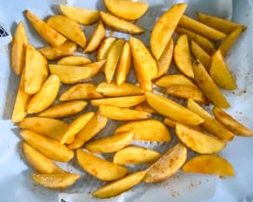 Spiced potato wedges placed on a parchment paper