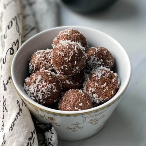 Chocolate Coconut balls in a white bowl; napkin with text on the side
