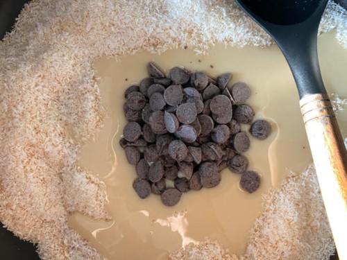 Condensed milk and chocolate chips added to coconut