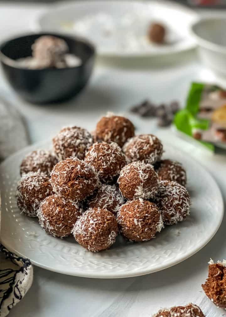 Chocolate coconut balls served in a white plate with chocolate chips in the background