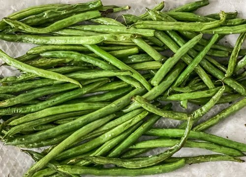 Air Fryer Green Beans (Asian-Style) in an air fryer basket lined with parchment paper cooked