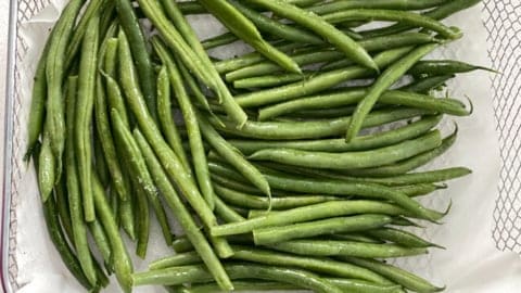 Air Fryer Green Beans (Asian-Style) in an air fryer basket lined with parchment paper uncooked