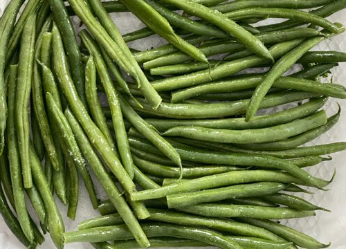 Air Fryer Green Beans (Asian-Style) in an air fryer basket lined with parchment paper uncooked