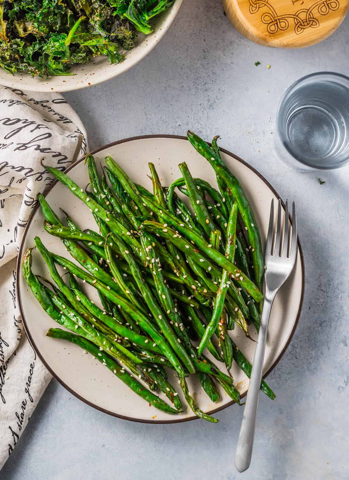Air Fryer Green Beans (Asian-Style) on a plate with a fork garnished with sesame seeds