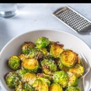 Brussels sprouts served in a white bowl with grated cheese