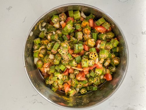 A bowl of cut okra and tomatoes, ready for preparing as bhindi masala.
