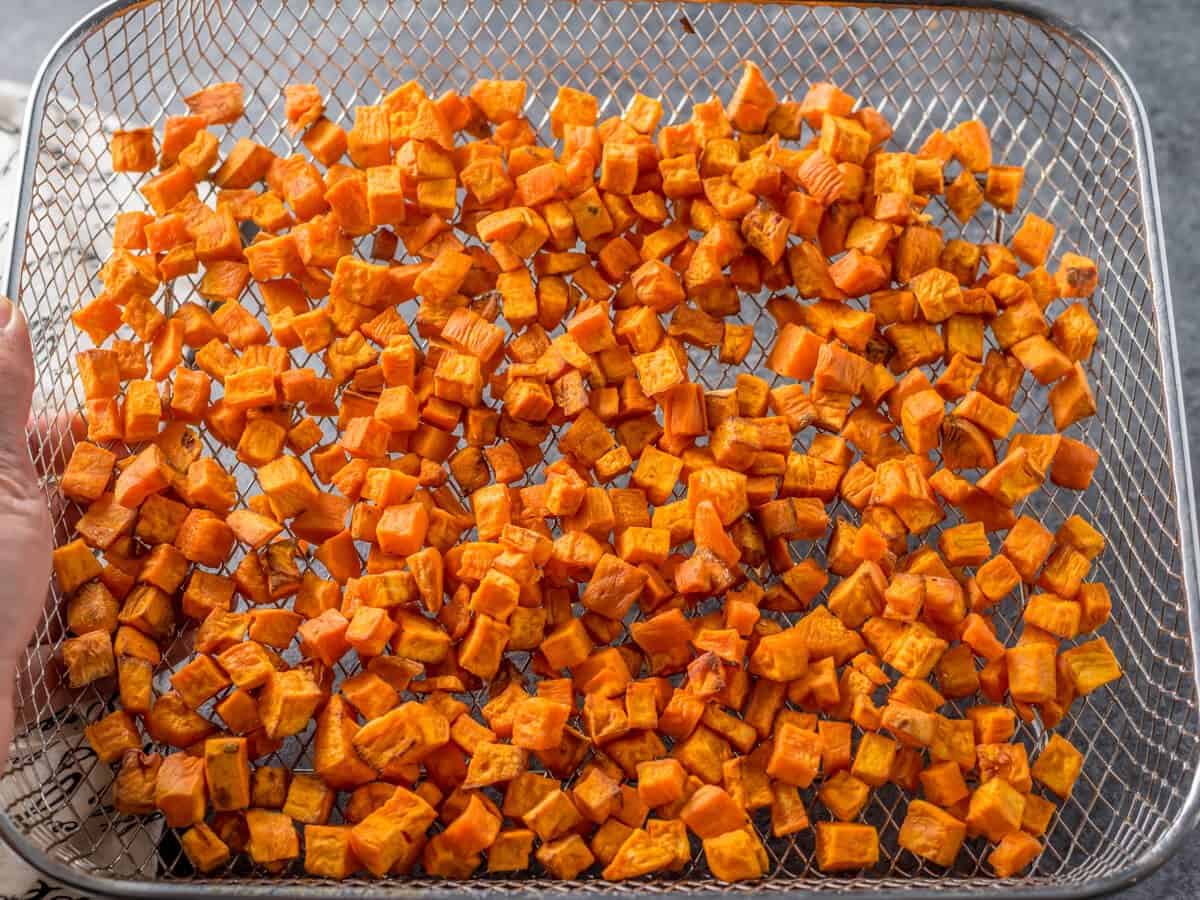 An air fryer tray of sweet potato chunks, cooked and slightly browned