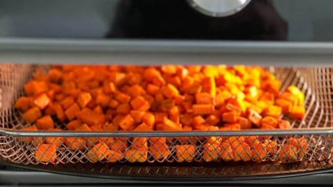 Air frying sweet potato cubes in a tray-style air fryer.