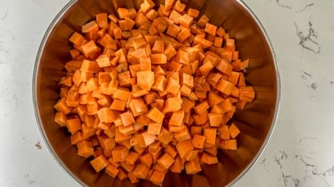 A bowl of sweet potato cubes, seasoned with a mixture of spices.
