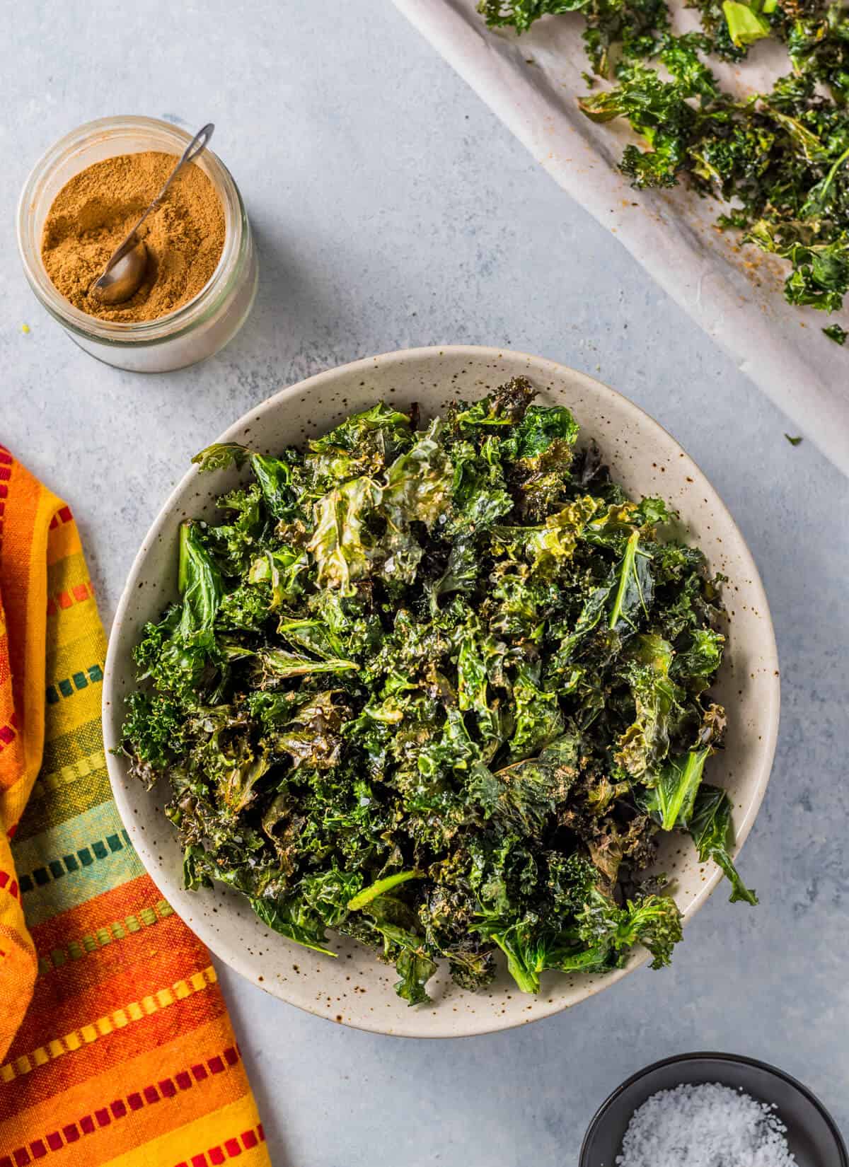 Kale chips in bowl with salt and chaat masala on the side