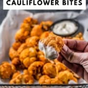 A hand dipping buffalo cauliflower wing into a creamy dipping sauce.