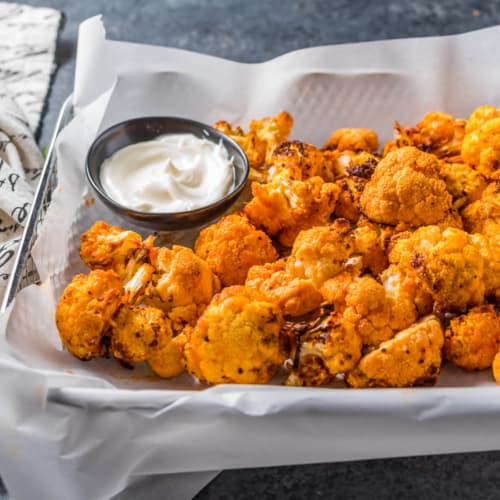 A tray of buffalo cauliflower with ranch dipping sauce on the side.