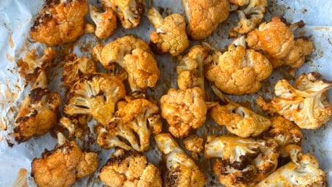 A tray full of cauliflower florets that have been coated in buffalo seasoning and butter, and then air fried until crisp.