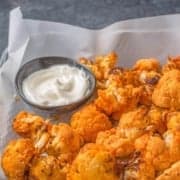 A tray of buffalo cauliflower bites with a creamy sauce on the side. The text overlay reads: air fryer cauliflower wings.