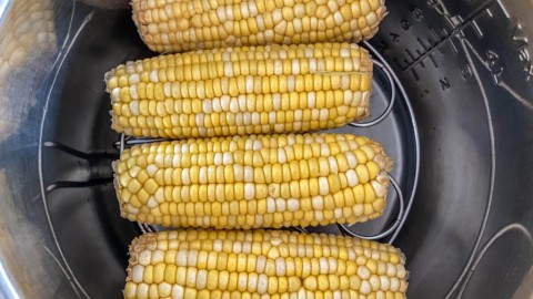 Stacking corn on the cob on top of an Instant Pot trivet inside of the pot.