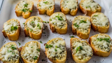 Baguette garlic bread slices, topped with chopped fresh parsley.