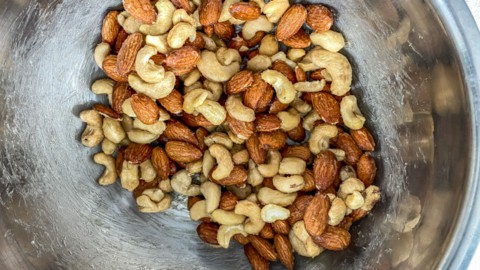 Almonds, Cashews in a steel bowl mixed with honey, ghee and salt
