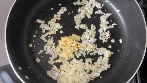 Adding onions and green chilies to a skillet.