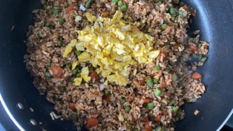 A skillet with fried rice, and a bit of egg on top.