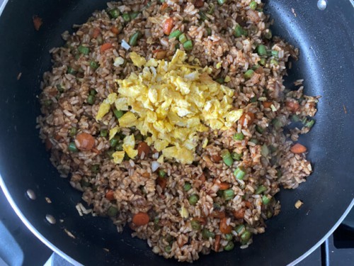 A skillet with fried rice, and a bit of egg on top.