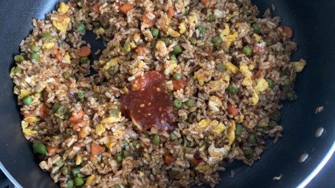 A skillet full of fried brown rice and vegetables.