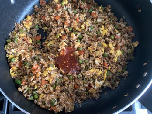A skillet full of fried brown rice and vegetables.