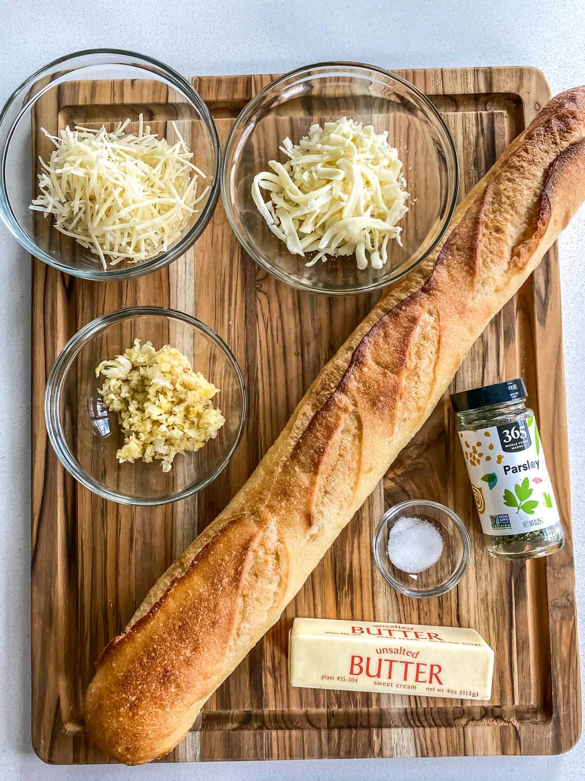 The ingredients needed to make air fryer garlic bread, including a baguette, cheese, and butter.