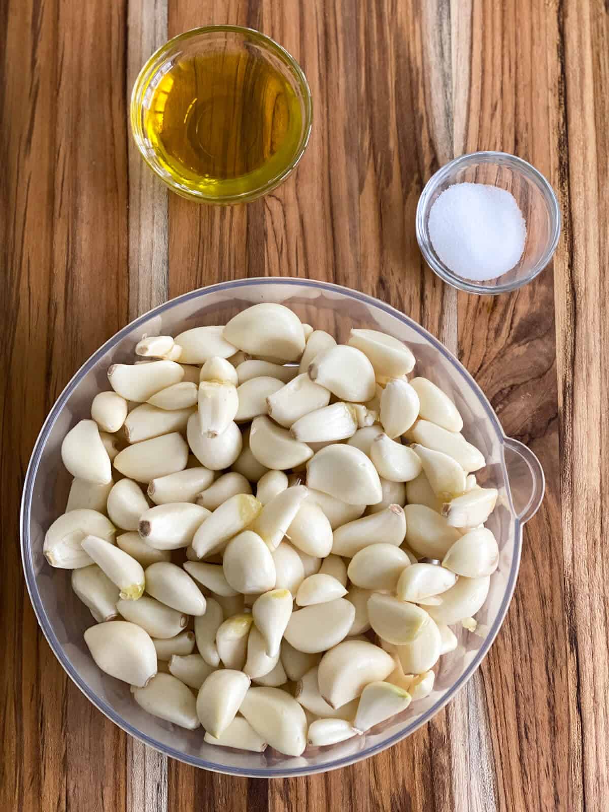 The ingredients needed to make garlic paste. Includes garlic cloves, oil, and salt.