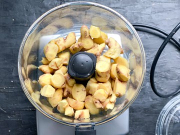 Adding chopped ginger to a food processor.
