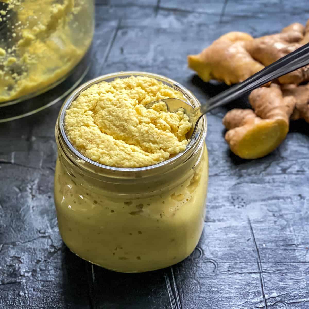 A jar of ginger paste with a spoon in it.