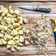 A cutting board with peeled ginger chopped into small pieces.
