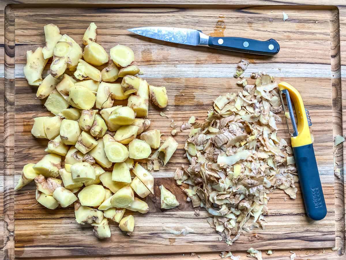 Peeling ginger root with a vegetable peeler.