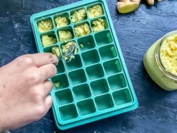Homemade ginger paste being added to a silicone ice cube tray.
