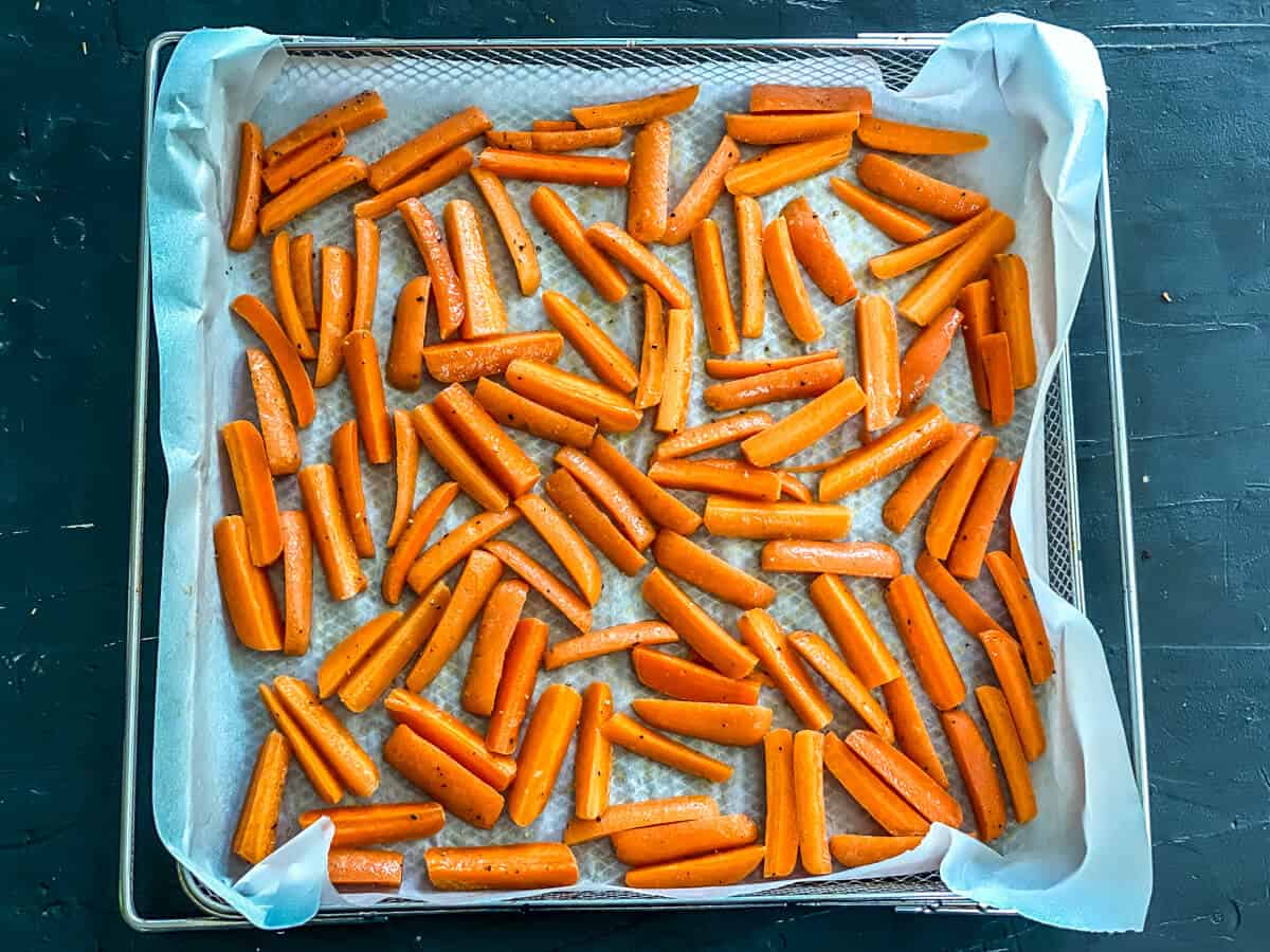 A parchment lined tray with carrot sticks on it.