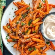 A plate of carrot fries with a creamy dip on the side.