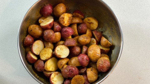 Potatoes being tossed with oil and seasonings.