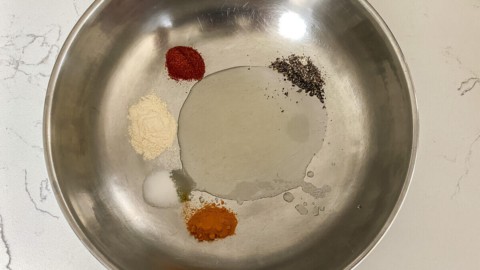 Adding oil and seasoning to a large bowl.