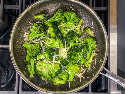 A top down photo of steamed broccoli in a non-stick skillet with parmesan cheese.