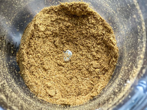 A spice grinder with powdered coriander seeds.