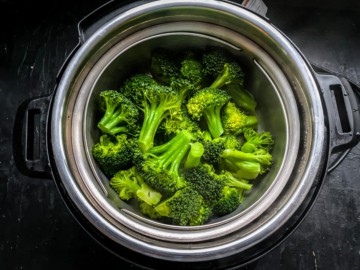 A steamer basket with steamed broccoli in the instant pot.