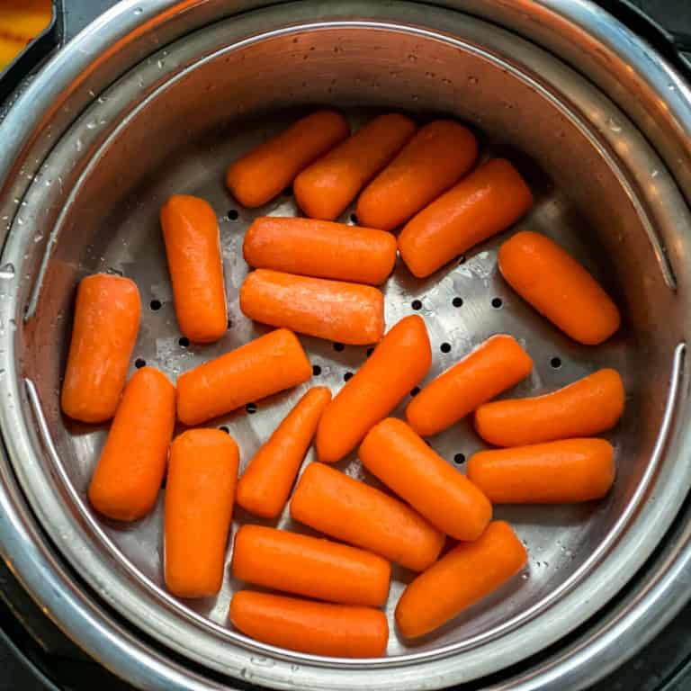 An instant pot steamer basket with baby carrots after steaming.
