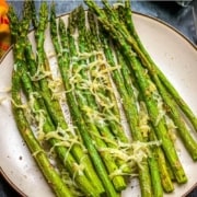 A cream plate with air fryer asparagus topped with parmesan and the words Make This At Home Air Fryer Asparagus at the top.