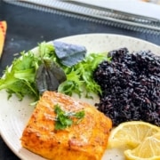 A small fillet of salmon served with salad and rice.