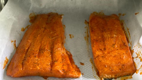 Salmon on a sheet of parchment paper, fully cooked.