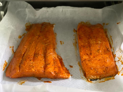 Salmon on a sheet of parchment paper, fully cooked.
