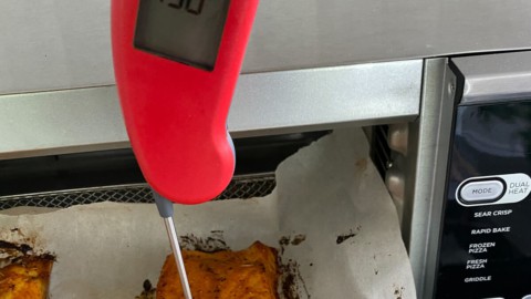 Checking the internal temperature of a filet of salmon.
