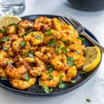 A plate of cooked shrimp, garnished with lemon and parsley.