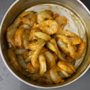 Stirring raw shrimp with seasoning in a bowl.