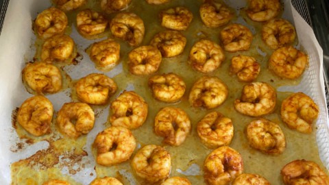 Cooked shrimp on a parchment lined air fryer tray.
