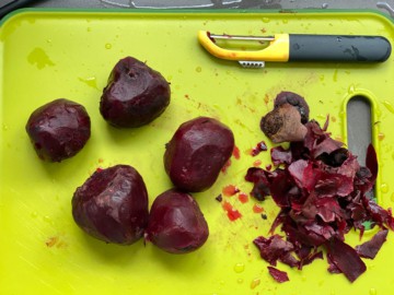 A wearing workbench with a peeler and peeled beets.